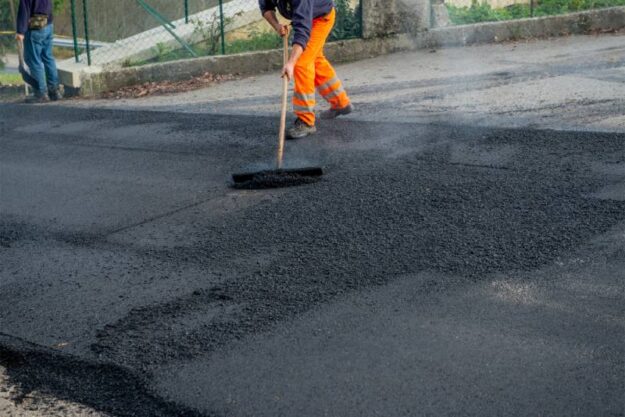 Asphalt pavers coating a new road in asphalt pavement.