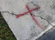 Concrete sidewalk marked with red "X" for repair.